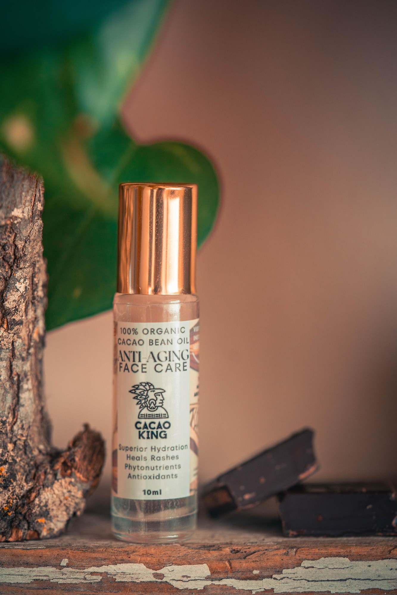 A bottle of cacao oil on a wooden shelf, cacao bars blurred behind it
